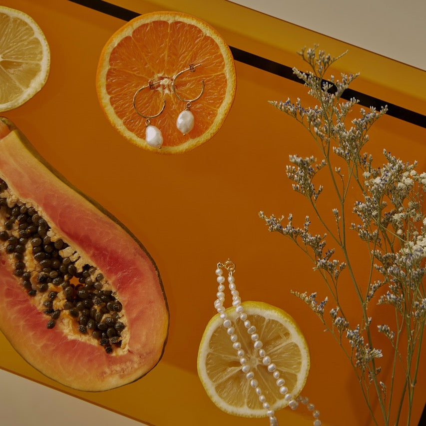Assiette de verre orange avec collier de perles